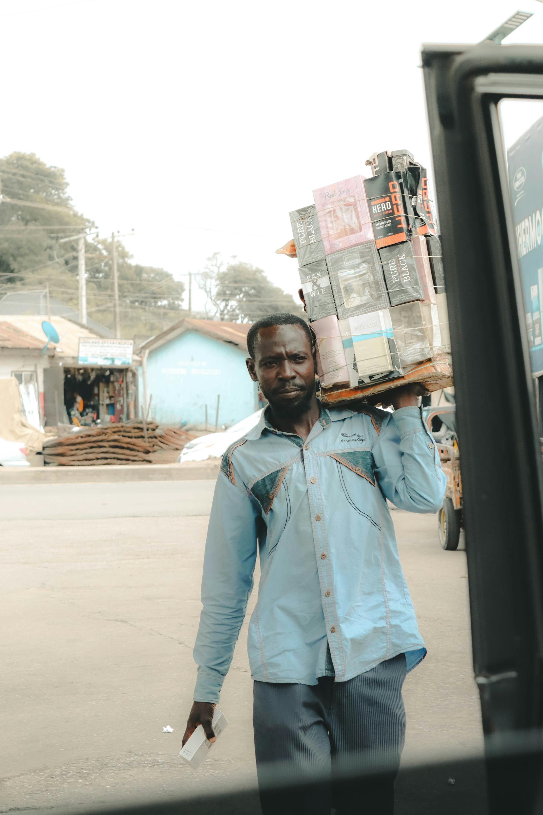 Nigerian courier carrying stacked packages in an urban area